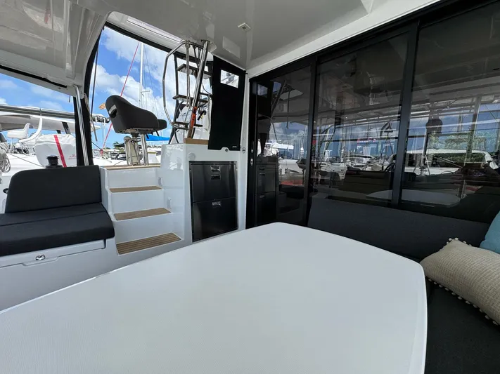 Bluevana Yacht Photos Pics Interior of 2023 Lagoon 42 catamaran with seating, table, and stairs, docked at marina.