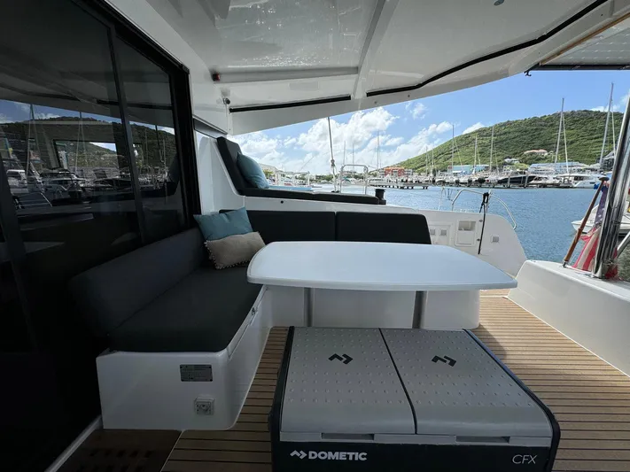 Bluevana Yacht Photos Pics 2023 Lagoon 42 yacht deck with seating, table, and scenic marina view.