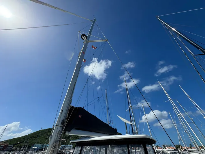 Bluevana Yacht Photos Pics Sailboat mast of 2023 Lagoon 42 against clear blue sky in marina.