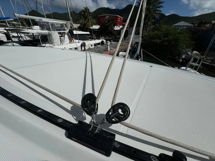 Bluevana Yacht Photos Pics 2023 Lagoon 42 catamaran deck with rigging and pulleys in a marina setting.