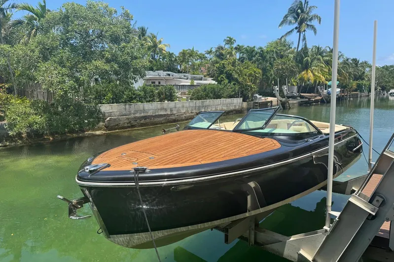  Yacht Photos Pics 2018 Chris-Craft Capri 27 boat on lift, surrounded by lush greenery and calm water.