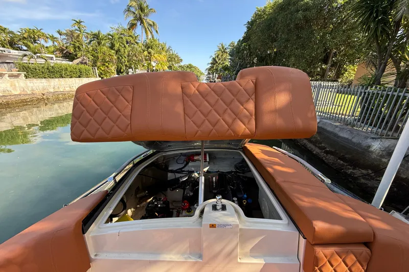  Yacht Photos Pics 2018 Chris-Craft Capri 27 boat with open engine compartment, brown leather seating, and lush surroundings.