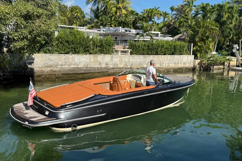  Yacht Photos Pics 2018 Chris-Craft Capri 27 boat on calm water, surrounded by lush greenery.