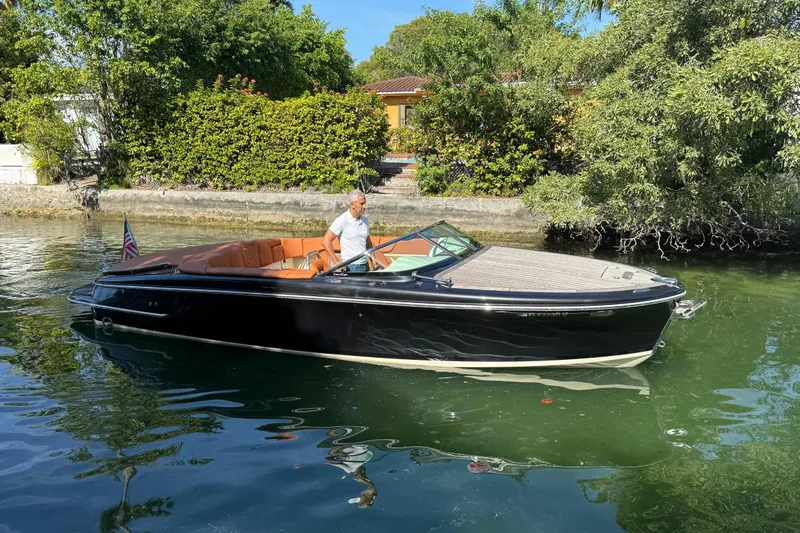  Yacht Photos Pics 2018 Chris-Craft Capri 27 boat on calm water, surrounded by lush greenery.