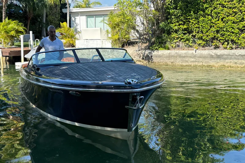  Yacht Photos Pics 2018 Chris-Craft Capri 27 boat on water, surrounded by lush greenery.
