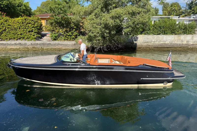  Yacht Photos Pics 2018 Chris-Craft Capri 27 boat on calm water, featuring sleek black design and tan interior.