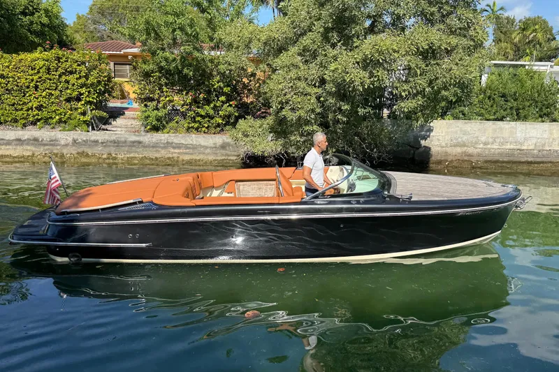  Yacht Photos Pics 2018 Chris-Craft Capri 27 boat cruising on a calm waterway, surrounded by lush greenery.