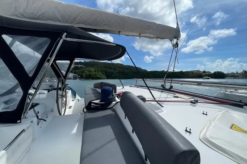 Tikiaora Yacht Photos Pics 2008 Lagoon 500 catamaran deck with seating, under sunny skies and scenic water view.