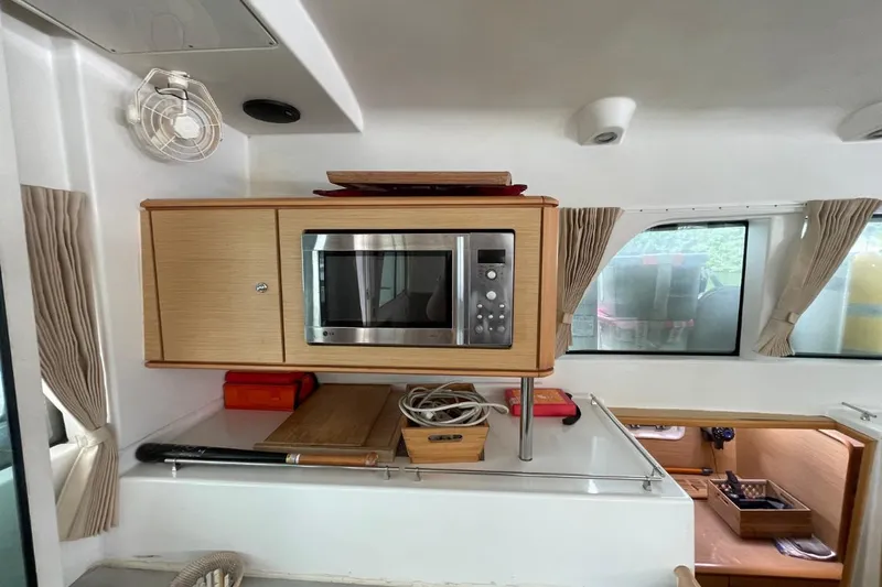 Tikiaora Yacht Photos Pics Interior of 2008 Lagoon 500 yacht with microwave, wooden cabinetry, and windows.