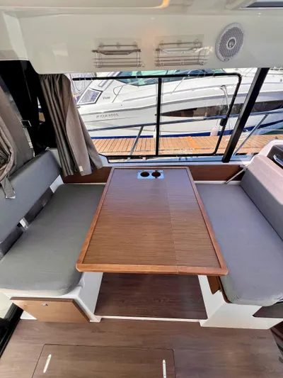  Yacht Photos Pics Interior of 2019 Jeanneau NC 1095 boat with wooden table and gray seating.