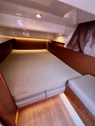  Yacht Photos Pics Cozy cabin interior of 2019 Jeanneau NC 1095 with wood accents and soft lighting.