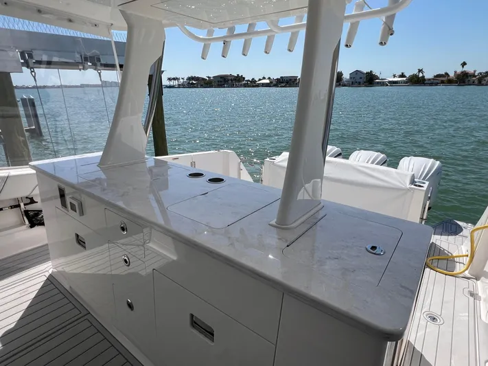  Yacht Photos Pics 2022 Regal 38 SAV yacht with sleek outdoor kitchen overlooking serene waterfront.