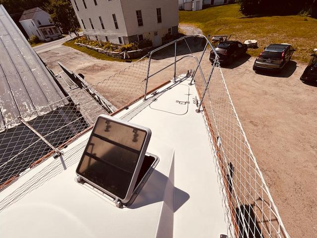 Sailboat deck of 1986 Pearson 28 with open hatch and safety netting.