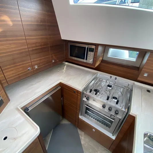 New Boat Built To Order Yacht Photos Pics Modern kitchen in a 2025 Southerly 480 yacht with wood cabinetry and stainless steel appliances.