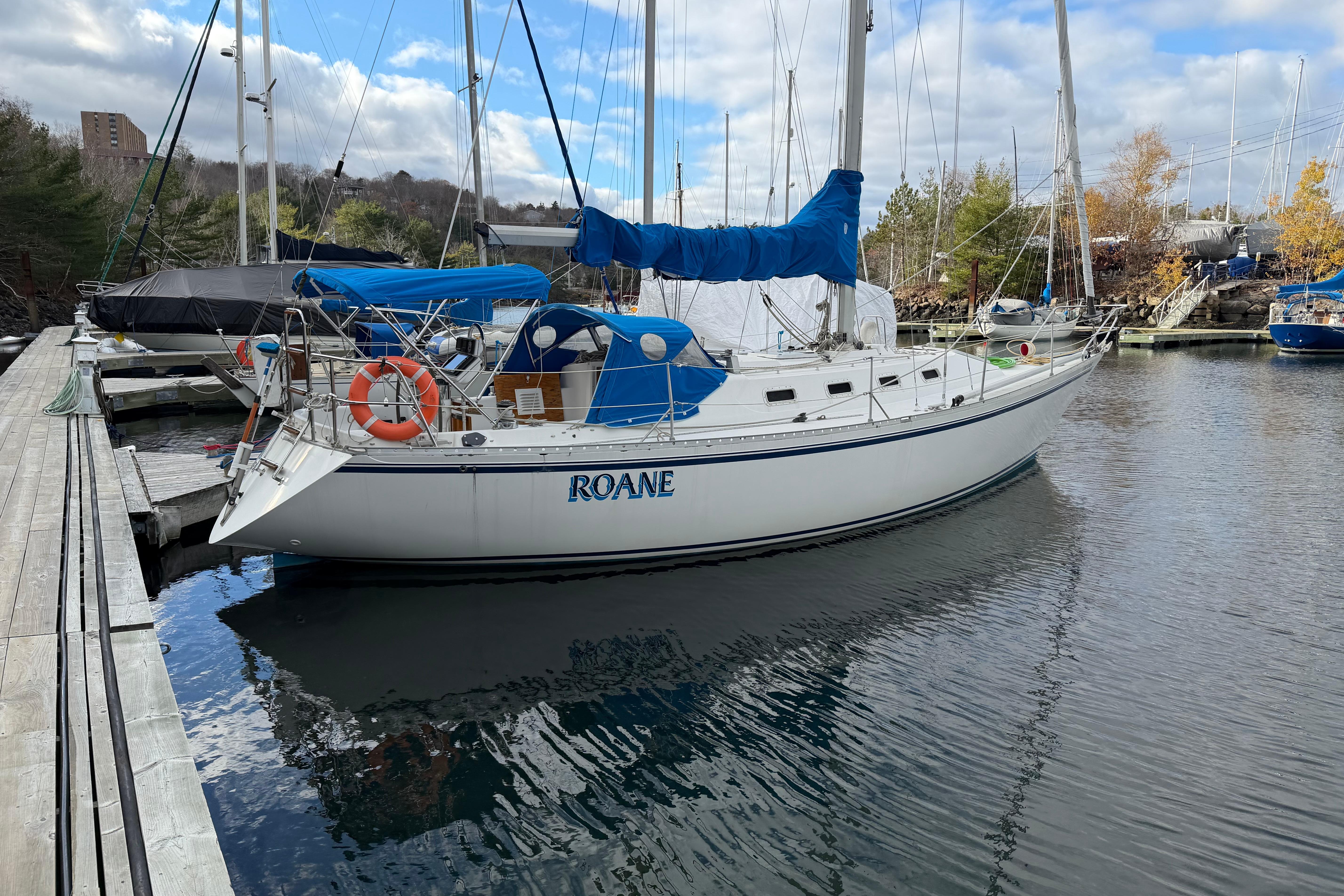 1985 CS 36 sailboat docked at marina, featuring blue covers and lifebuoy.