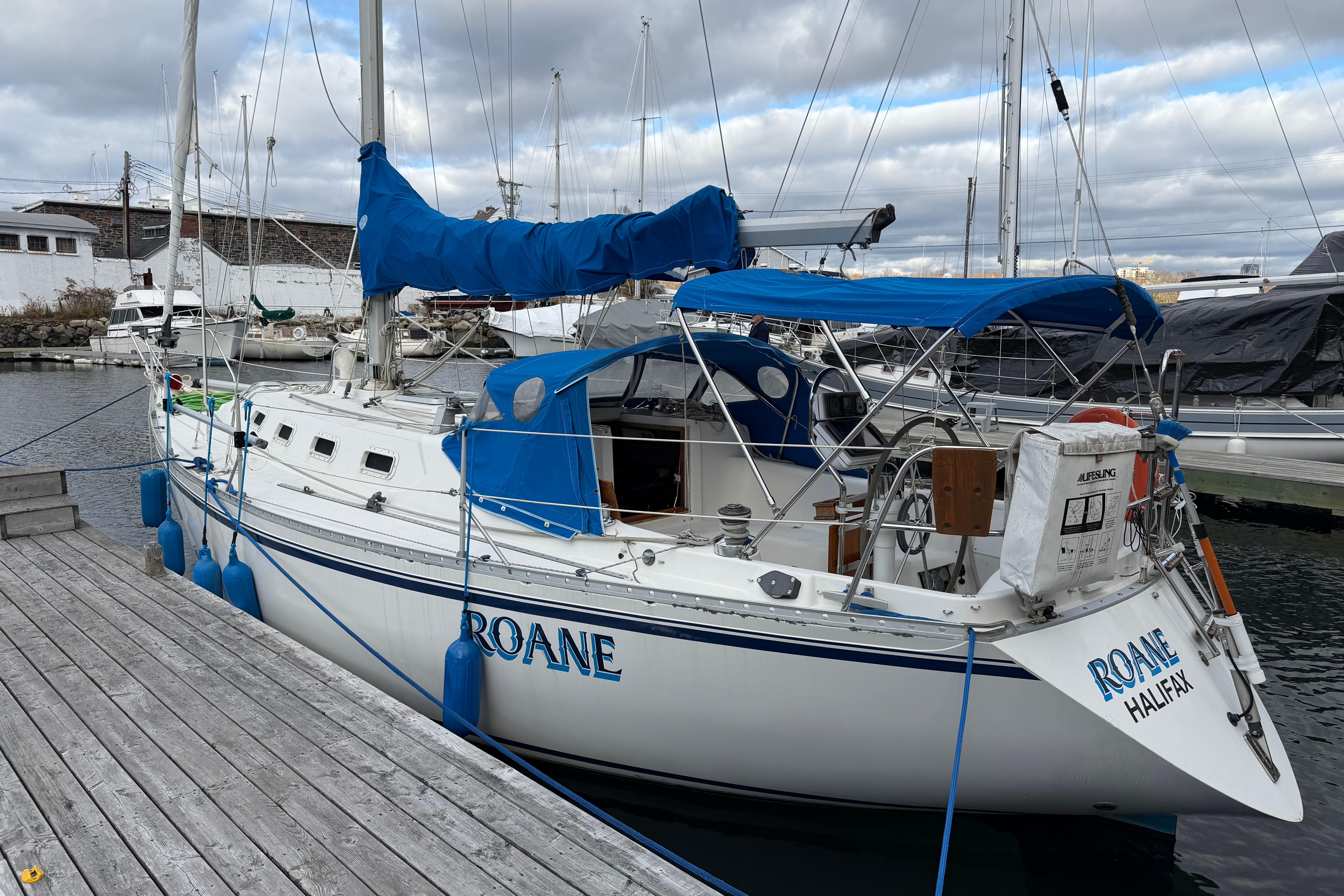1985 CS 36 sailboat docked at marina, featuring blue covers and "Roane" name.