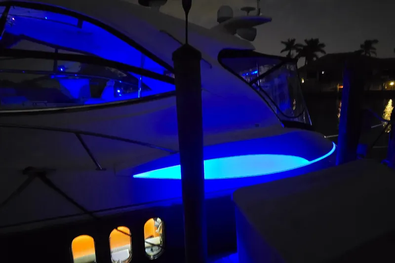  Yacht Photos Pics 2006 Cruisers Yachts 520 Express with blue LED lights at night, docked near palm trees.