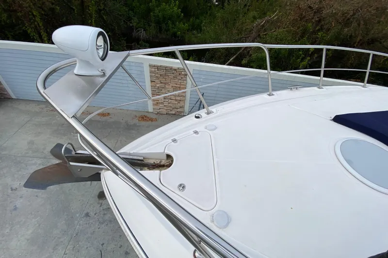  Yacht Photos Pics 2006 Cruisers Yachts 520 Express bow with anchor and spotlight, docked near a fence.