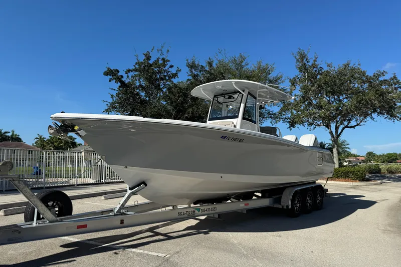  Yacht Photos Pics 2025 Sea Hunt Ultra 305 SE boat on trailer, parked outdoors under clear blue sky.