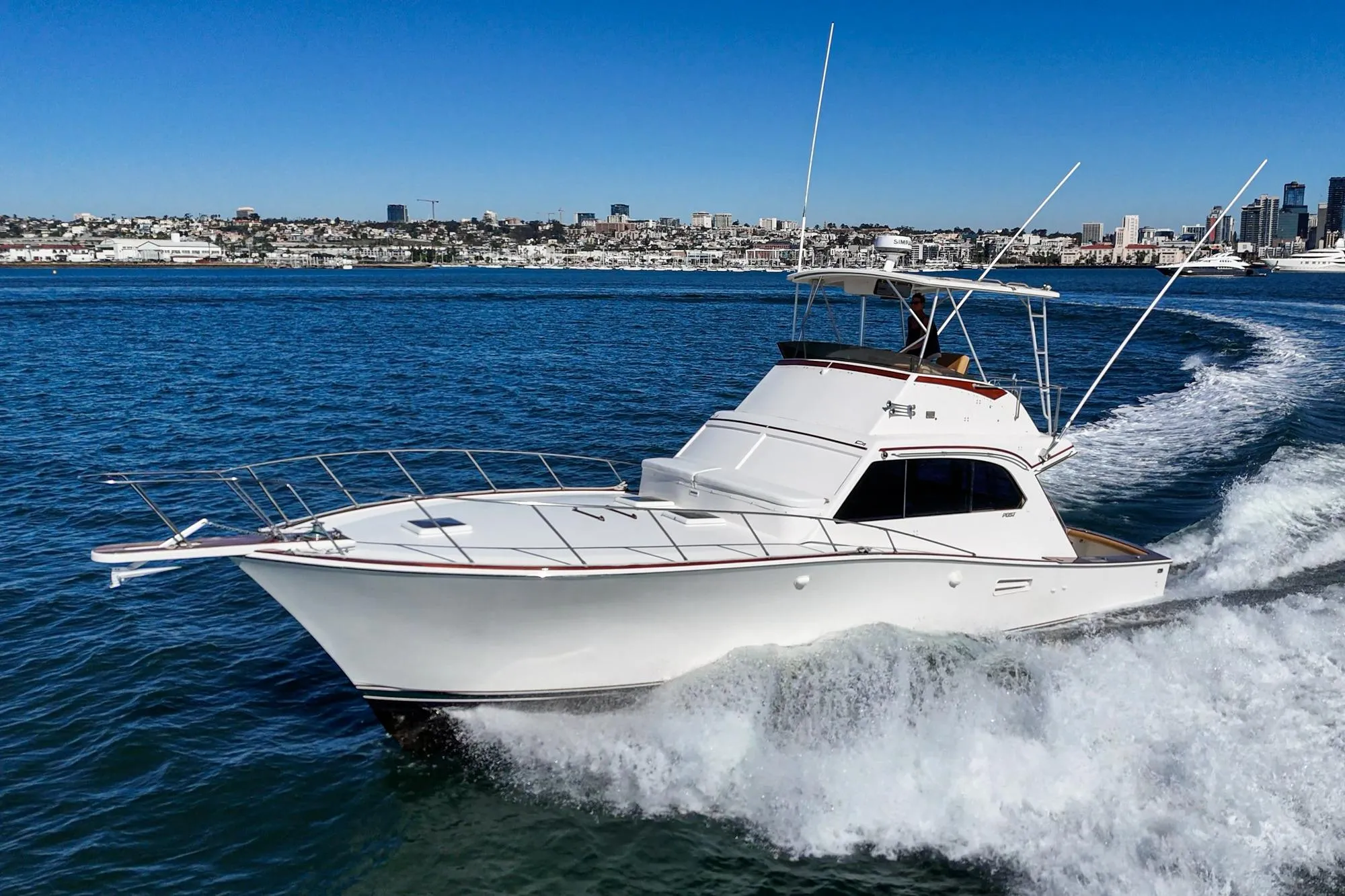 1984 Post 43 yacht cruising on blue ocean near city skyline.
