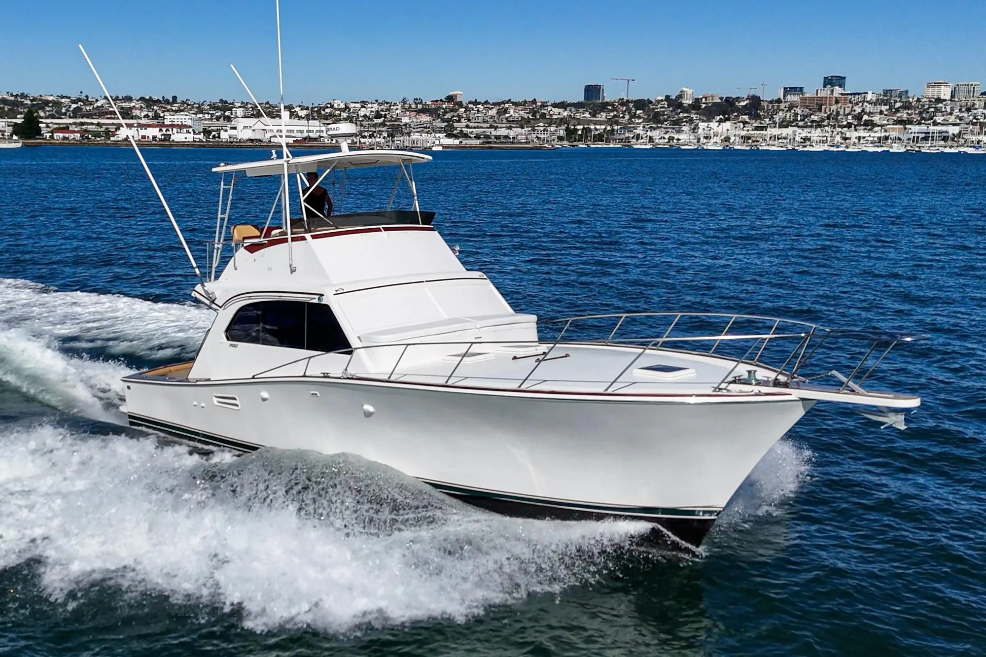 1984 Post 43 yacht cruising on blue ocean near city skyline.