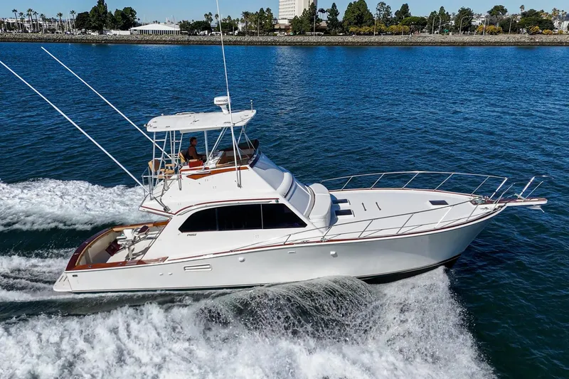 Un Dia Yacht Photos Pics 1984 Post 43 yacht cruising on blue water near a scenic shoreline.