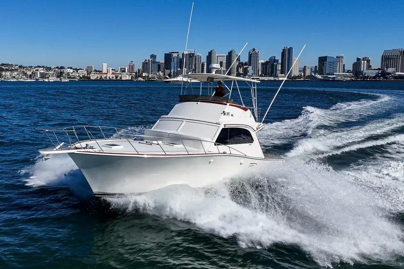 Un Dia Yacht Photos Pics 1984 Post 43 yacht cruising on water with city skyline in background.