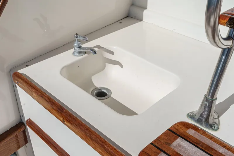 Un Dia Yacht Photos Pics White sink with chrome faucet on a 1984 Post 43 boat, featuring wooden accents.