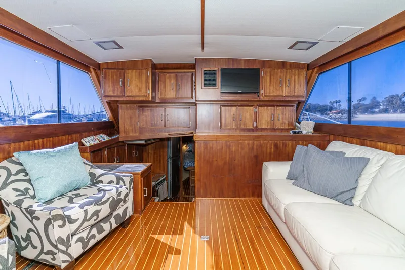 Un Dia Yacht Photos Pics Luxurious 1984 Post 43 yacht interior with wood paneling, plush seating, and scenic marina views.
