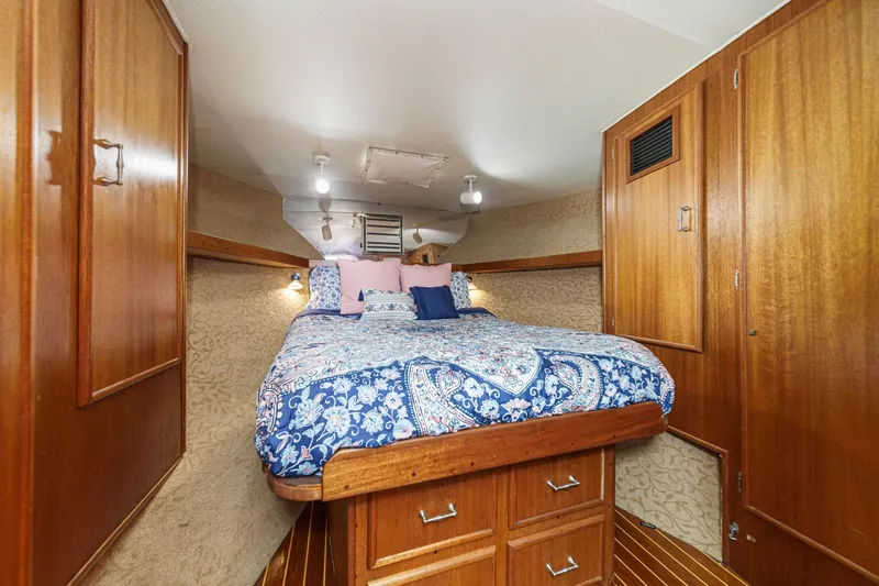 Un Dia Yacht Photos Pics Cozy cabin interior of 1984 Post 43 yacht with wooden furnishings and patterned bedding.