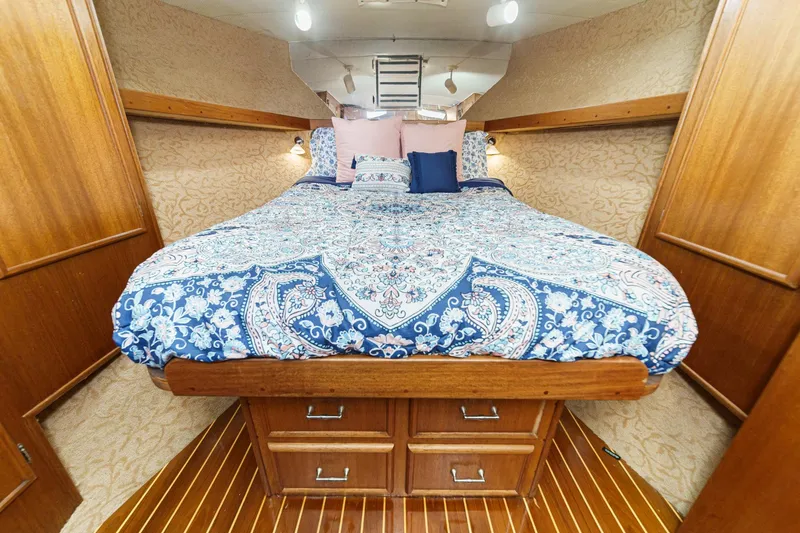 Un Dia Yacht Photos Pics Cozy bedroom in 1984 Post 43 boat with patterned bedding and wooden accents.