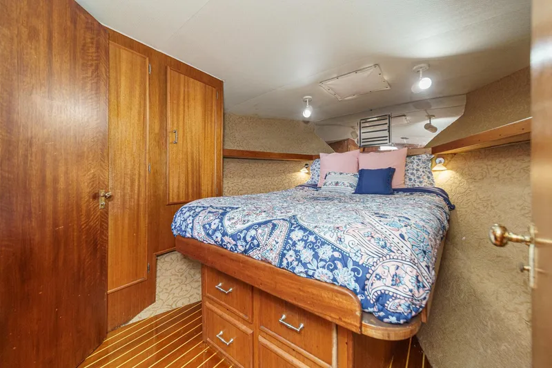 Un Dia Yacht Photos Pics Cozy bedroom in 1984 Post 43 boat with wooden cabinets and patterned bedding.