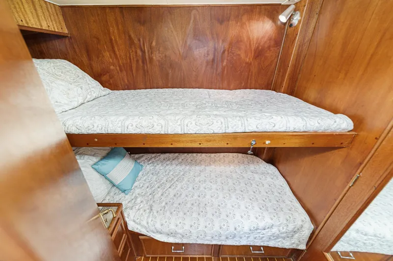 Un Dia Yacht Photos Pics Bunk beds in a 1984 Post 43 yacht cabin with wood paneling and patterned bedding.