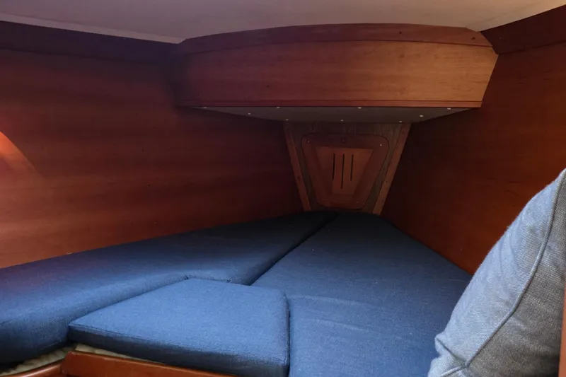 Orion Yacht Photos Pics Interior cabin of a 1997 Freedom 35 sailboat with blue cushions and wooden paneling.