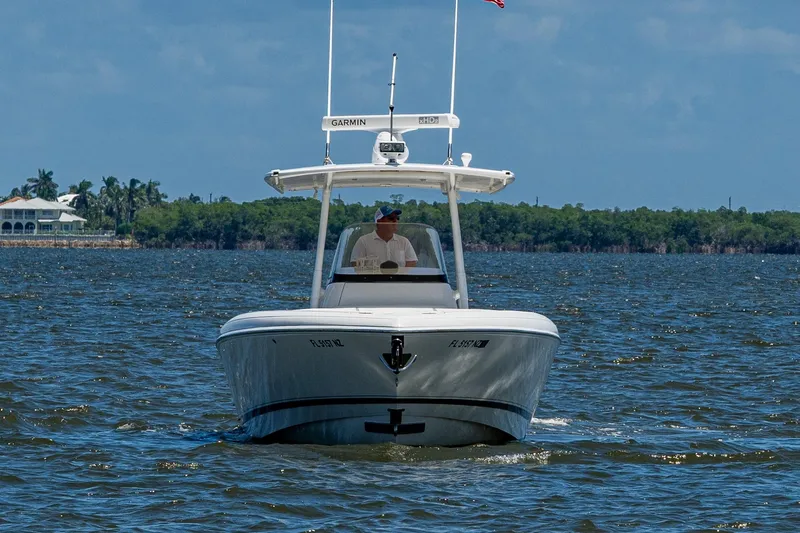  Yacht Photos Pics 2010 Intrepid 323 OPEN boat cruising on a sunny day with lush shoreline backdrop.