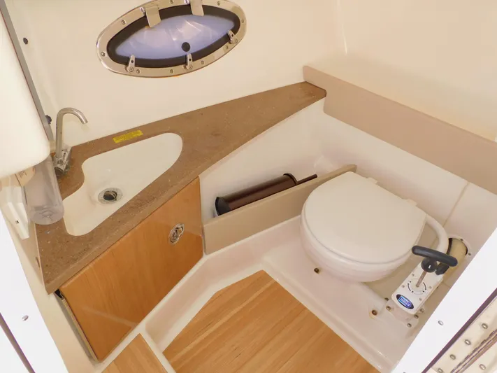 Tide Runner Yacht Photos Pics 2015 Formula Bowrider 290 boat bathroom with sink, toilet, and wooden cabinetry.