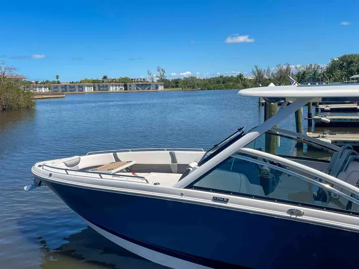  Yacht Photos Pics 2021 Chaparral 300 OSX boat docked on a serene lake under a clear blue sky.