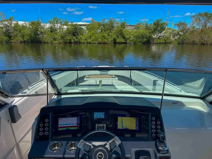  Yacht Photos Pics Cockpit view of 2021 Chaparral 300 OSX boat with navigation screens on a calm river.