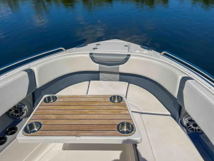  Yacht Photos Pics 2021 Chaparral 300 OSX boat interior with cushioned seating and wooden table on calm water.