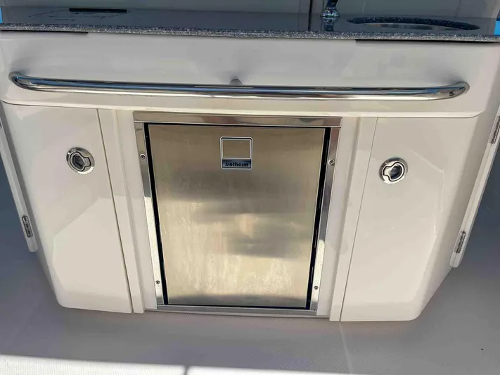  Yacht Photos Pics 2021 Chaparral 300 OSX boat kitchenette with stainless steel fridge and storage compartments.