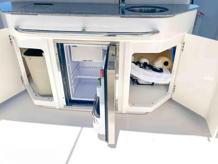  Yacht Photos Pics 2021 Chaparral 300 OSX boat kitchenette with open cabinets and mini fridge.