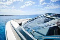2004 Mangusta 80 Open yacht cruising on clear blue ocean under a sunny sky.