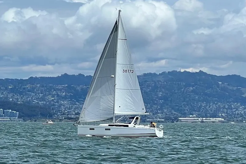 Grand Cru Yacht Photos Pics 2018 Beneteau Oceanis 38.1 sailboat cruising on a scenic lake with hills in the background.