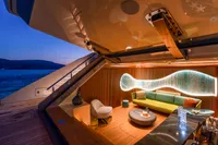 Luxurious yacht interior with modern seating, ambient lighting, and ocean view at sunset, Bilgin Custom 2023.
