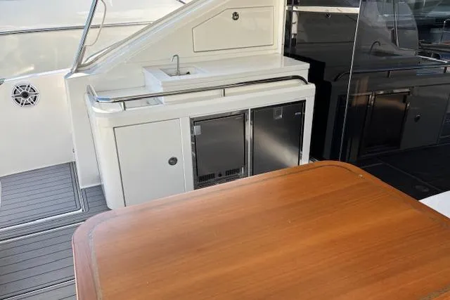  Yacht Photos Pics 2020 Riviera 4800 Sport Yacht outdoor kitchenette with sink and wooden table.