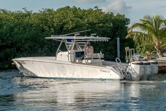  Yacht Photos Pics 2015 Bahama 34 boat on water, surrounded by lush greenery and palm trees.