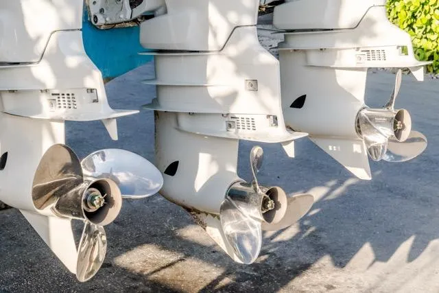  Yacht Photos Pics Three outboard motors on a 2015 Bahama 34 boat, showcasing shiny propellers.