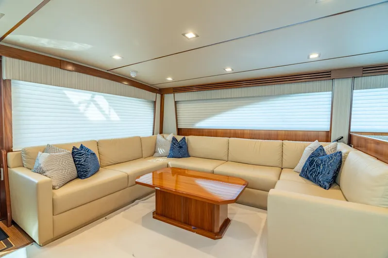 Reel Cents Yacht Photos Pics Luxurious interior of 2019 Viking 80 Enclosed Bridge yacht with beige seating and wooden table.
