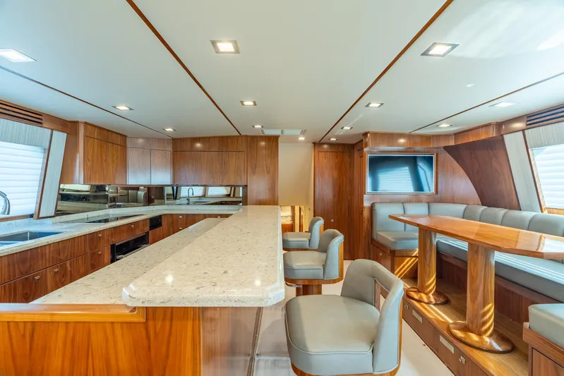 Reel Cents Yacht Photos Pics Luxurious interior of 2019 Viking 80 Enclosed Bridge yacht with modern kitchen and seating area.
