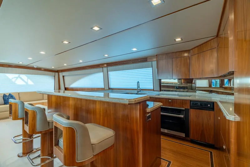 Reel Cents Yacht Photos Pics Luxurious interior of 2019 Viking 80 Enclosed Bridge yacht with modern kitchen and seating.